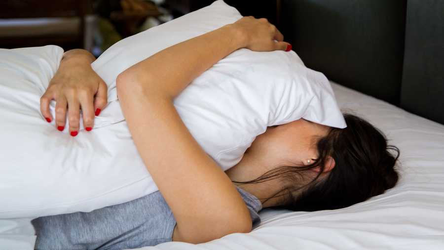 woman holding pillow over her body and face
