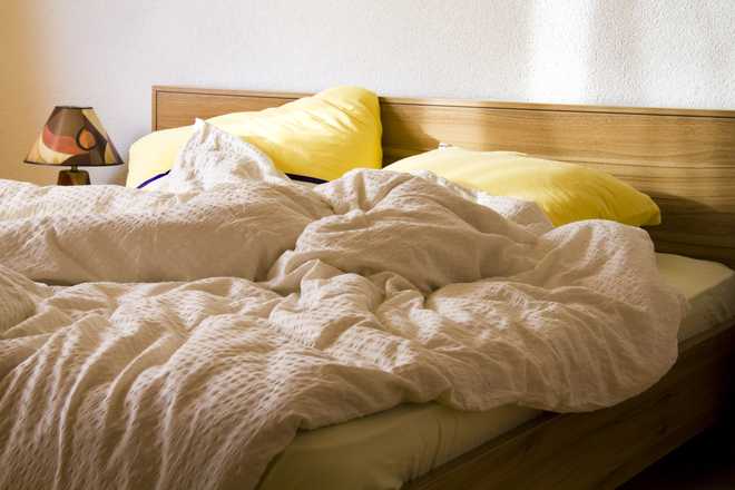 an unmade bed with yellow pillows in the morning