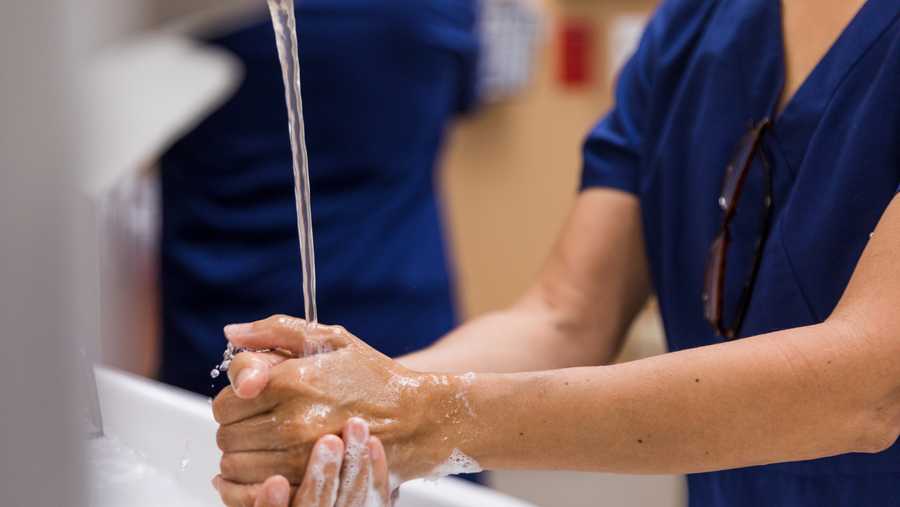 close up medical worker washing hands with soap and water