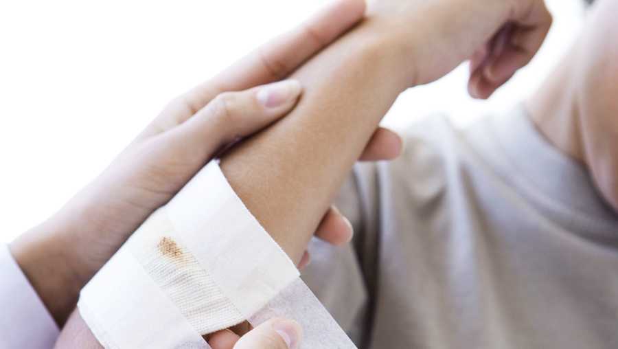 Doctor applying gauze to child's arm, cropped view