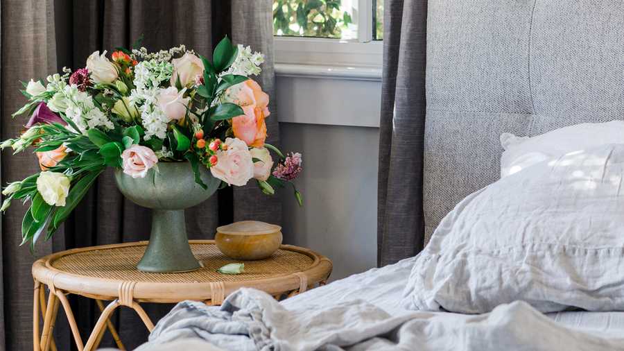 flowers in vase next to bed