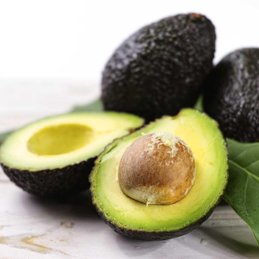 Green ripe avocado with leaves close up Green ripe avocado with leaves close up