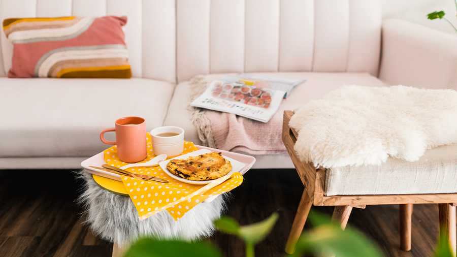 living room with pink velvet couch and coffee on fur ottoman