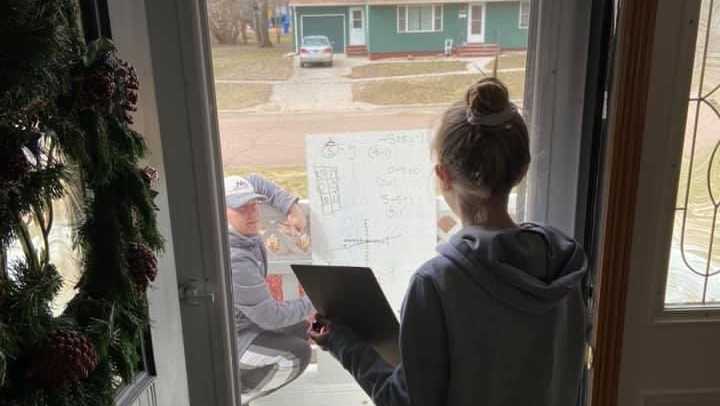 This sixth-grade teacher from South Dakota is shown helping a student with a homework assignment on her front porch during the coronavirus outbreak.