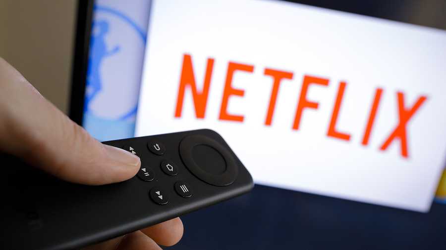 A remote points toward a TV that's loading Netflix shows.