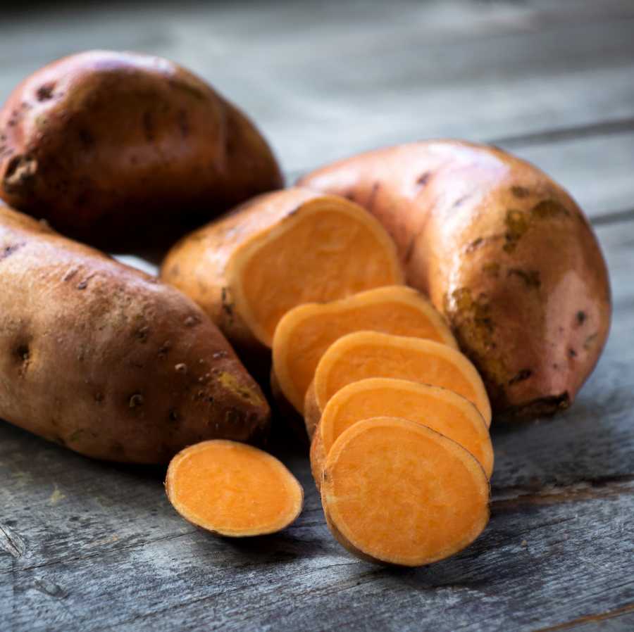 Raw sweet potatoes on wooden background closeup Raw sweet potatoes on wooden background closeup