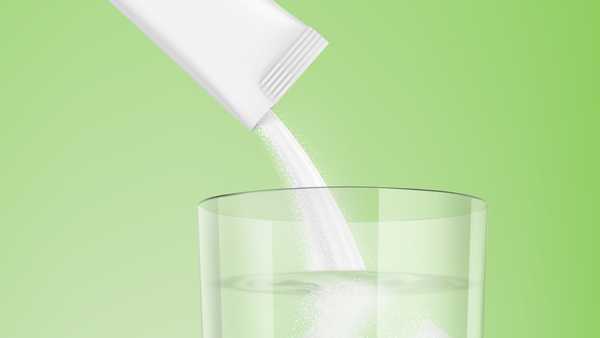 stick pack pouring powder product in clear glass with liquid.