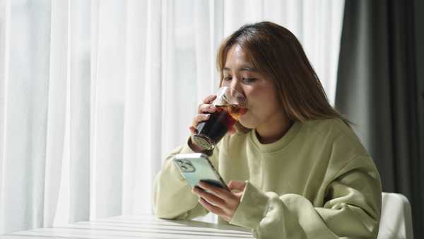 woman drink cola while using smartphone