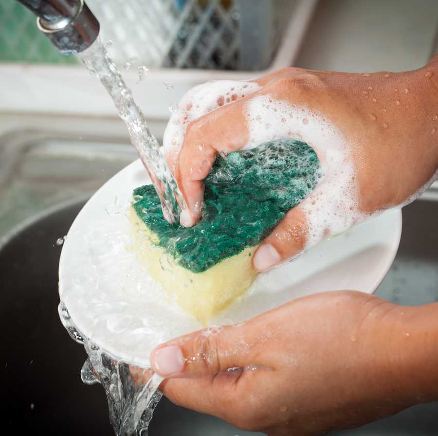 woman hand washing dishes over the sink in the kitchen