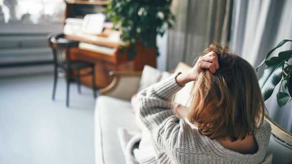 a woman with her back to the camera is lying on a sofa in a beautiful room with a piano