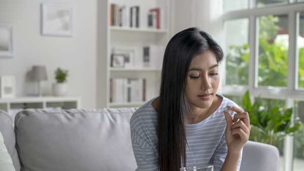 young woman taking pill and vitamin in the living room