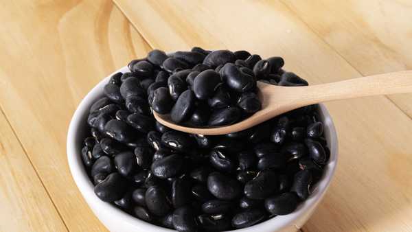 Black Beans in wooden spoon with ceramic bowl.