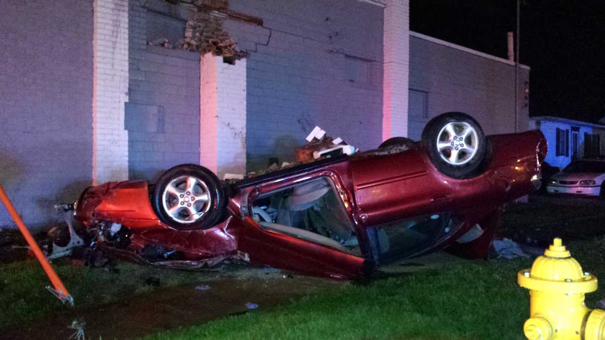 Driver found in flipped car after it hit building