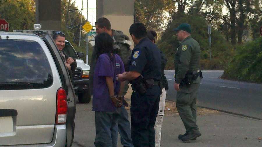 Uniformed officers detain a person found during a warrant sweep Wednesday morning.