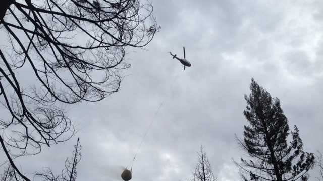 A helicopter carries a netful of rice straw to the King Fire burn zone.