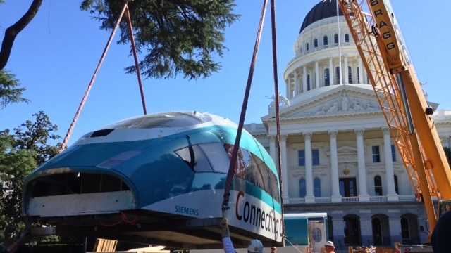 A crane unloads a high-speed rail model at the state Capitol in Sacramento.