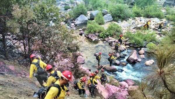 Pink fire retardant was laid down by planes and crews climbed through the steep terrain to get to the Kyburz Fire.