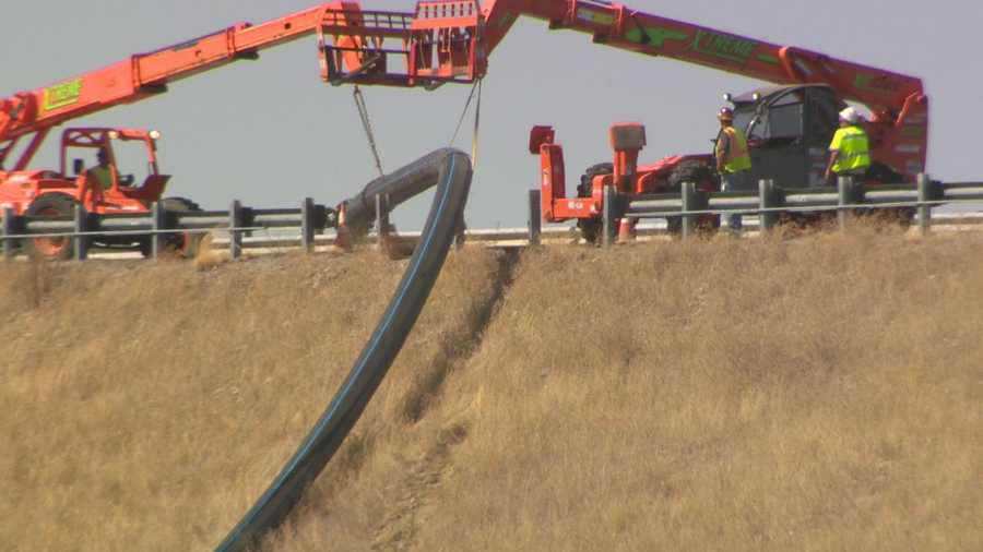 Crews install pipes across the top of Folsom Dam to prepare for lower water levels.