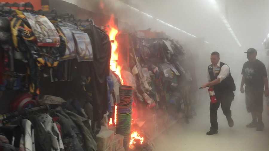 A Walmart employee uses a fire extinguisher to help contain a blaze set in the costume aisle of the store on Tuesday, Oct. 13, 2015.