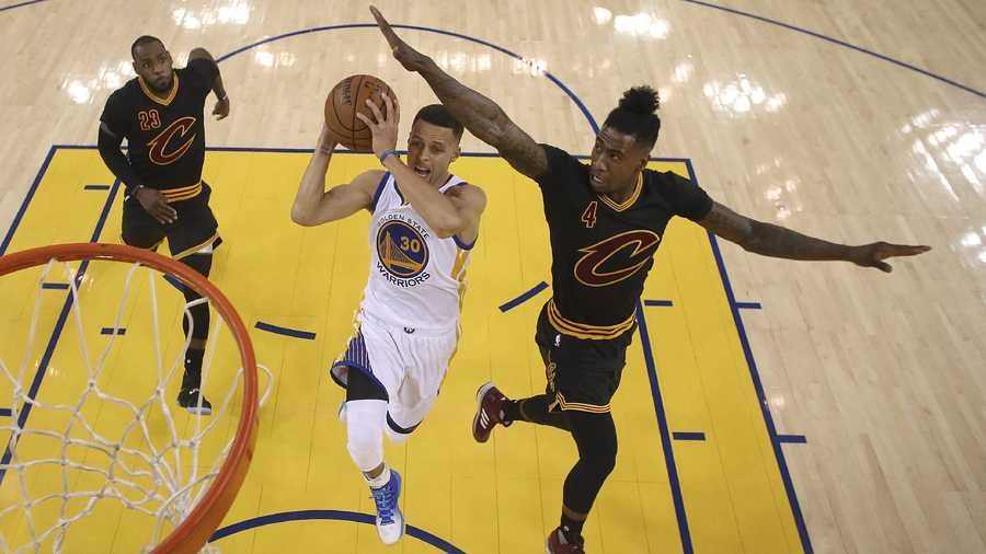 Golden State Warriors guard Stephen Curry (30) shoots between Cleveland Cavaliers forward LeBron James (23) and guard Iman Shumpert (4) during the first half of Game 5 of basketball's NBA Finals in Oakland, Calif., Monday, June 13, 2016.