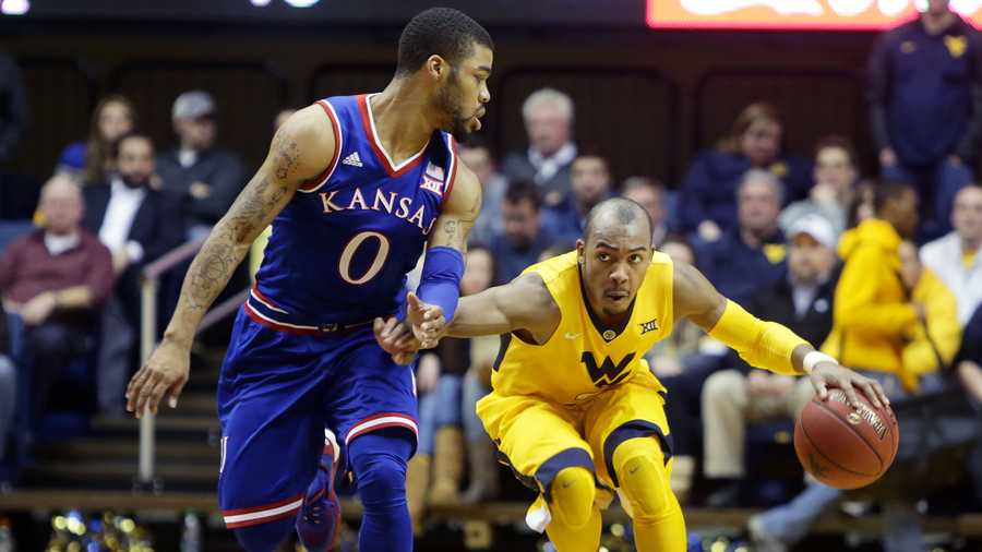 West Virginia guard Jevon Carter, right, drives up court while being defended by Kansas guard Frank Mason III (0) during the second half of an NCAA college basketball game, Tuesday, Jan, 12, 2016, in Morgantown, W.Va. West Virginia defeated Kansas 74-63.(AP Photo/Raymond Thompson)