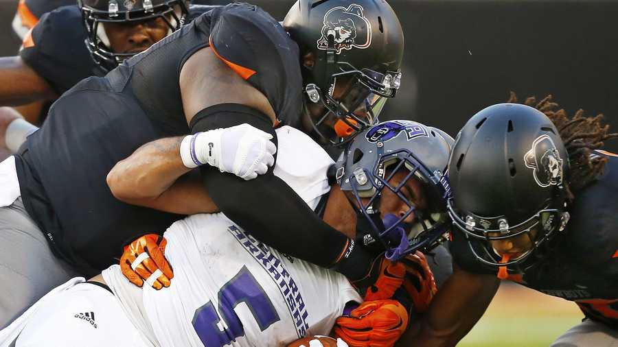 Central Arkansas running back Dominique Thomas (5) is tackled by a number of Oklahoma State defenders in the first quarter of an NCAA college football game in Stillwater, Okla., Saturday, Sept. 12, 2015. (AP Photo/Sue Ogrocki)