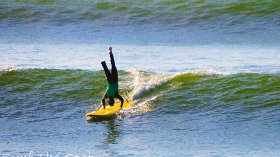 A soldier with one foot does a hand-stand while surfing off Cowell Beach during the 2011 Operation Surf.