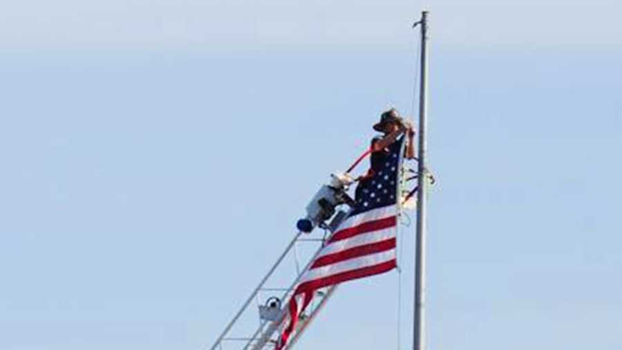 A Santa Cruz firefighter lowers a flag on top of the clock tower on Pacific Avenue. 