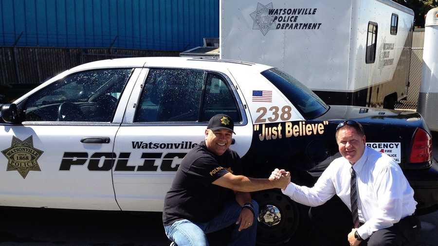Watsonville Police Chief Manny Solano shakes hands with police Lt. Terry Traub. Patrol cars were marked with "Just Believe" while the chief underwent treatment for cancer.