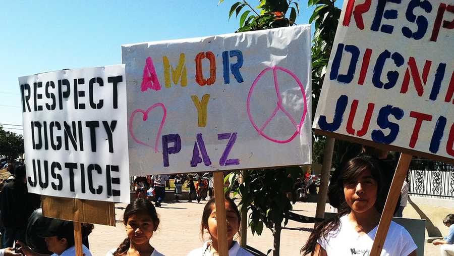 Girl hold signs calling for respect, dignity, justice, love, and peace during a march in East Salinas. (May 25, 2014)