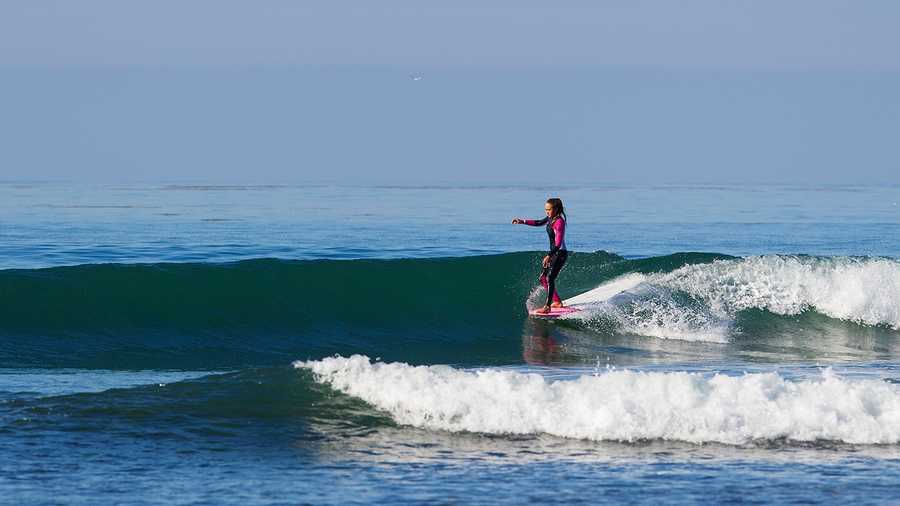 Meg Roh hangs five while riding her longboard on a fun glassy wave. 