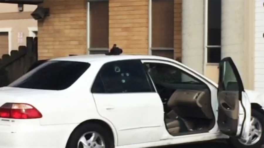 Bullet holes are seen on the victim's car. 