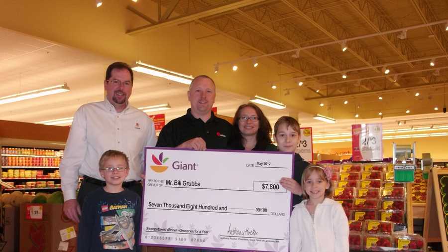 Jamie Miller (left), public and community relations manager for Giant Food of Landover, Md., presents the Year of Groceries Sweepstakes Winner Bill Grubbs with a check for $7,800 at the new Parkville Giant in Parkville, Md. Grubbs, joined by his wife and three children, will receive Giant Food gift cards, totaling $7,800 to spend on groceries at his neighborhood store.