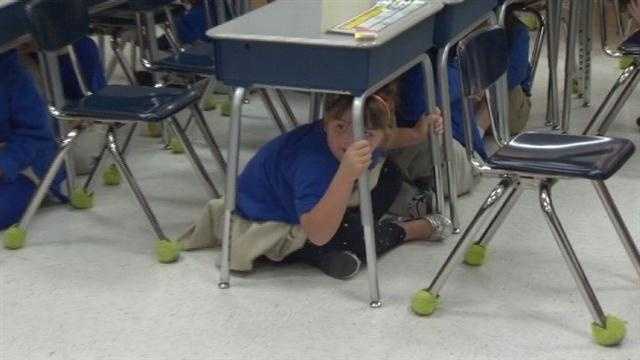 Baltimore City school students practice earthquake safety in class during a nationwide exercise.