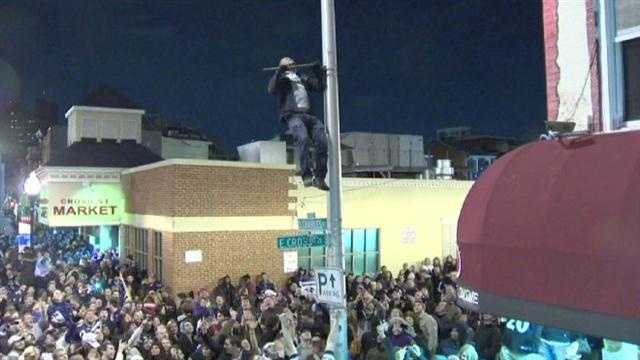 A man dangerously climbs up a light pole and tries to do pull-ups off part of it that was sticking out. 