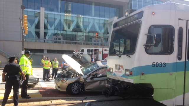 Two people were trapped in a car after their vehicle collided with a light rail train near the Baltimore Convention Center.