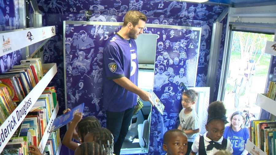 Ravens quarterback Joe Flacco hands out books to children at Abbottston Elementary School as the team unveils its bookmobile.