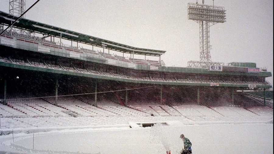 An unidentified grounds worker pushes a snow blower across the infield of Fenway Park.