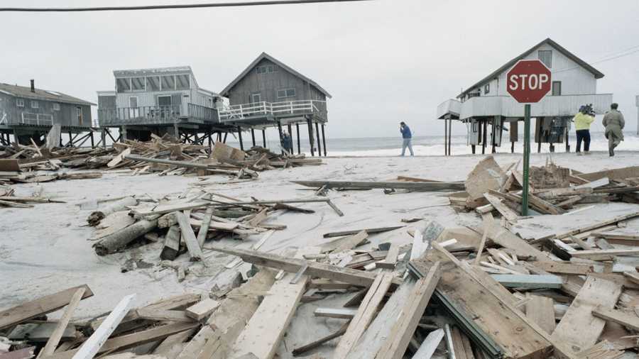 People survey the damage to home along Westhampton Beach after strong winds and high tides swept across the region.