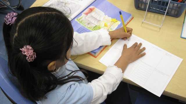 Girl in a classroom writing in a workbook