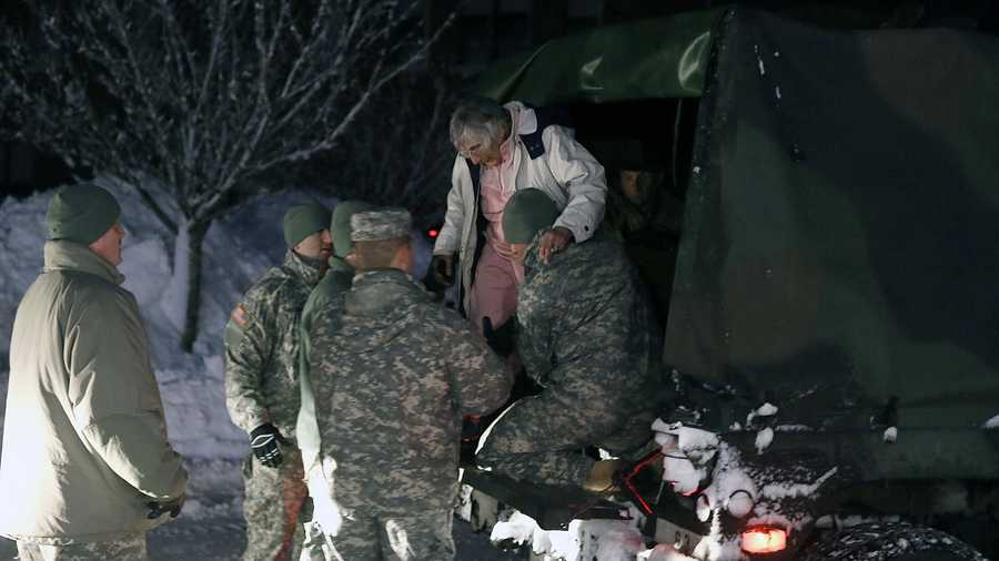 An evacuee is helped from the back of a National Guard truck in Marshfield in February 2013.