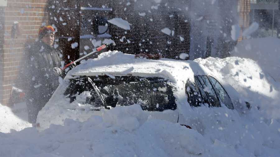 A woman on North street in the North End neighborhood of Boston, digs out her car as a neighbor runs a snow blower, Sunday, Feb. 10, 2013.