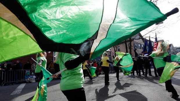 Women from the Sanford High School color guard, of Sanford, Maine, twirl green flags while marching in the St. Patrick’s Day Parade in South Boston.