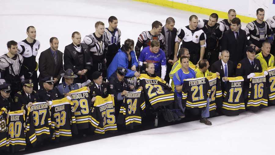 First responders, members of law enforcement and Boston Marathon officials hold Boston Bruins jerseys as they gather with members of the team, back, on the ice following an NHL hockey game against the Florida Panthers at the TD Garden in Boston, Sunday, April 21, 2013.
