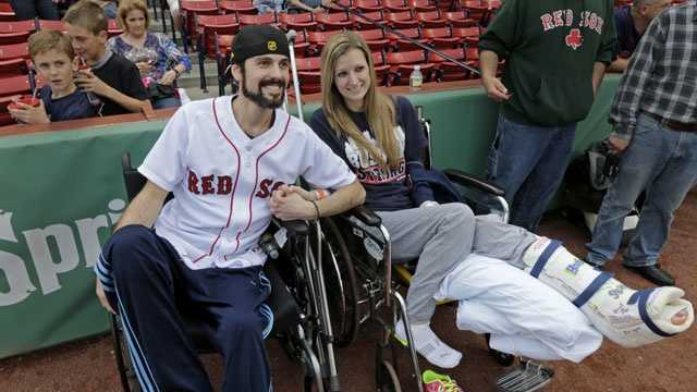 In this Thursday, May 23, 2013 photo, Boston Marathon bombing survivor Pete DiMartino, of Rochester, N.Y., and his girlfriend, Rebekah Gregory, hold hands prior to DiMartino throwing out the ceremonial first pitch before a Red Sox game at Fenway Park.