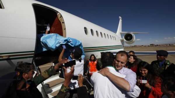 Dr. Joseph Currier, right, facing camera, embraces a Bolivian doctor, as a stretcher carrying four-year-old Rosalie is placed into a private plane at the airport in El Alto, Bolivia, Thursday, June 20, 2013.