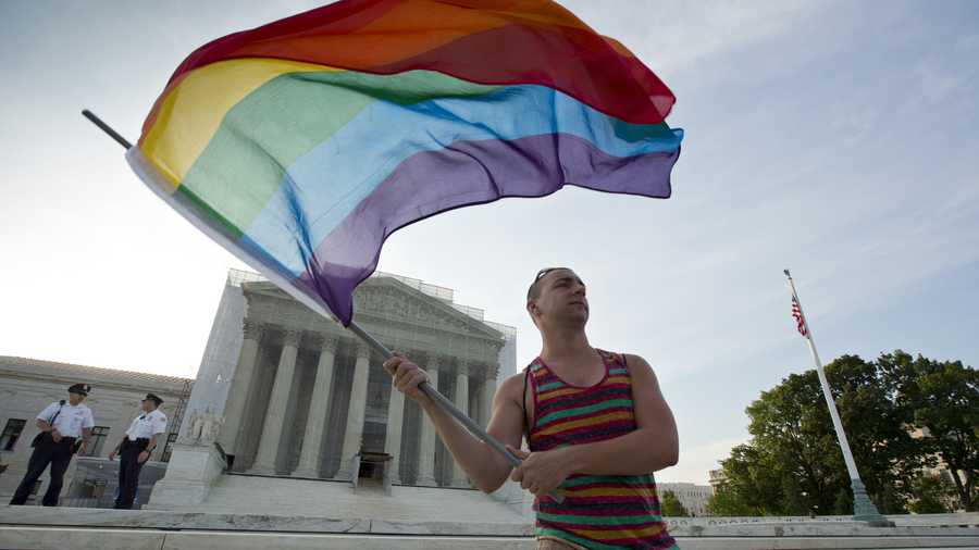 Gay rights advocate Vin Testa waves a rainbow flag in front of the Supreme Court at sun up in Washington, Wednesday, June 26, 2013.