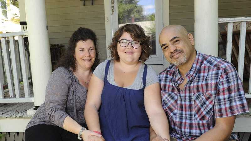 In this June 20, 2013 photo, Becky Bluh, left, and Tony Derricotte pose for a photo with their daughter, Cameron Bluh-Derricotte, center, at their home in Greenfield, Mass. The Make-A-Wish Foundation has arranged a trip to London for Cameron, who has a rare autoimmune disorder.