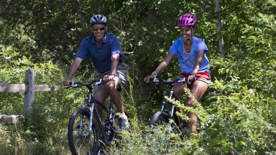 Malia Obama, right, followed by her father, President Barack Obama, ride their bikes in Manuel F. Correllus State Forest in West Tisbury, Mass., after first lady Michelle Obama, with daughter Sasha, passed by first, Friday, Aug. 16, 2013, during their family vacation on the island of Martha's Vineyard. 