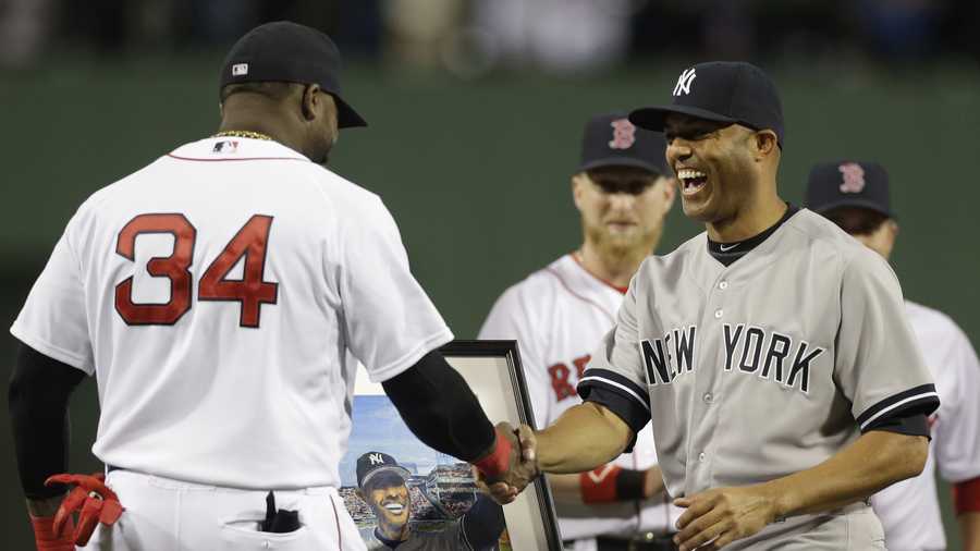 New York Yankees relief pitcher Mariano Rivera, right, shakes hands with Boston Red Sox's David Ortiz, left, as Ortiz presents him with a portrait, behind, during a tribute to Rivera before the start of a baseball game at Fenway Park, Sept. 15, 2013.